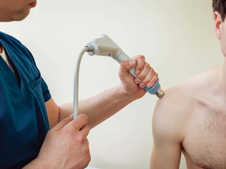 Hombre recibiendo terapias en el hombro con laser terapéutico